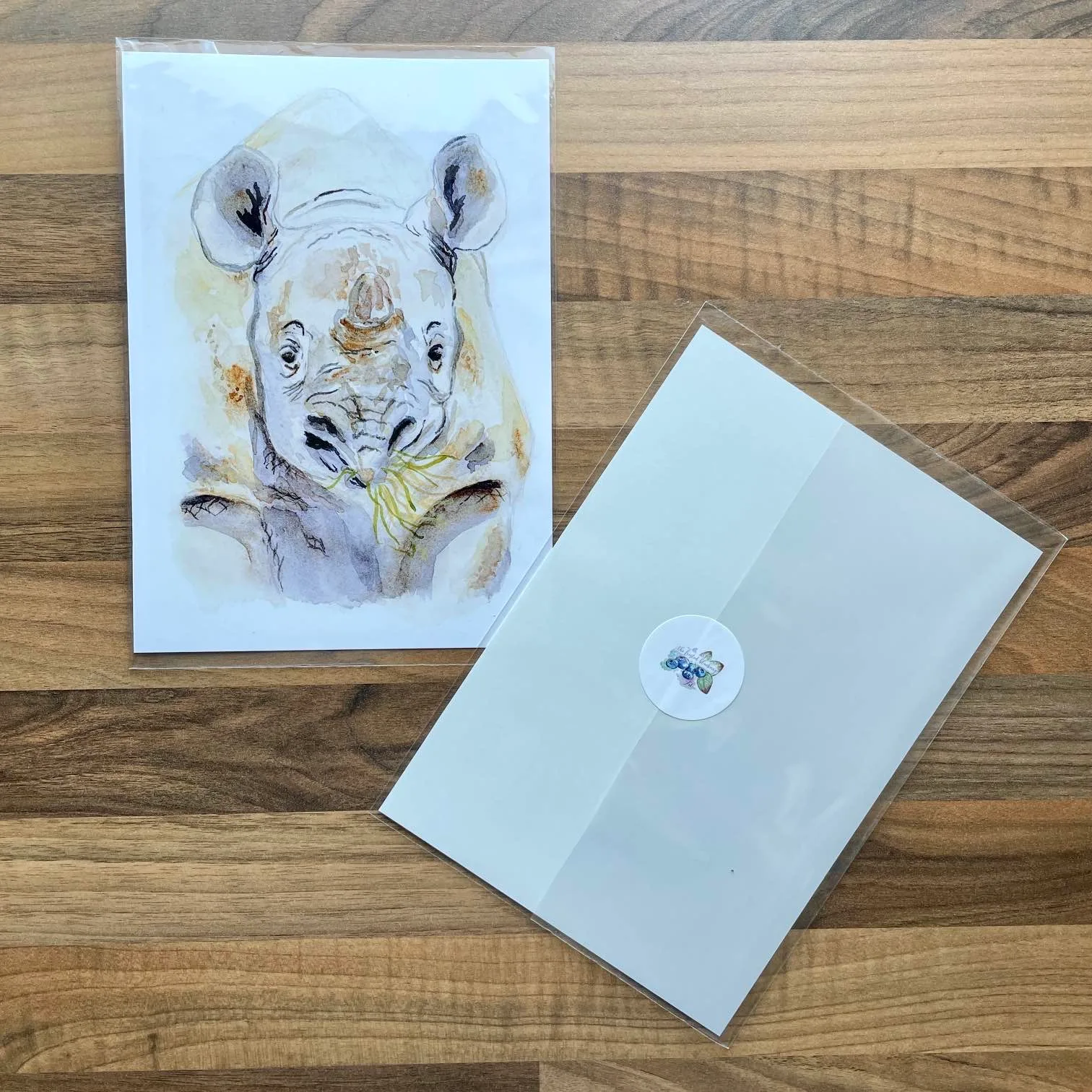 Watercolour painting of a rhino munching long grass