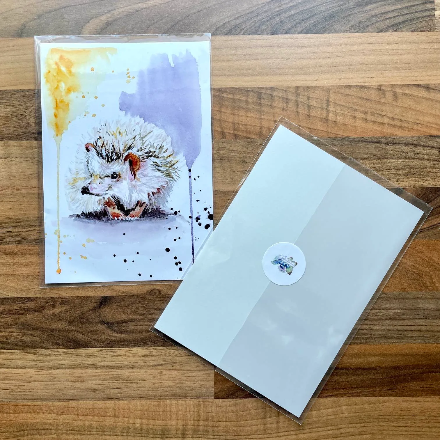 Watercolour painting of a hedgehog with playful purple and yellow paint splashes