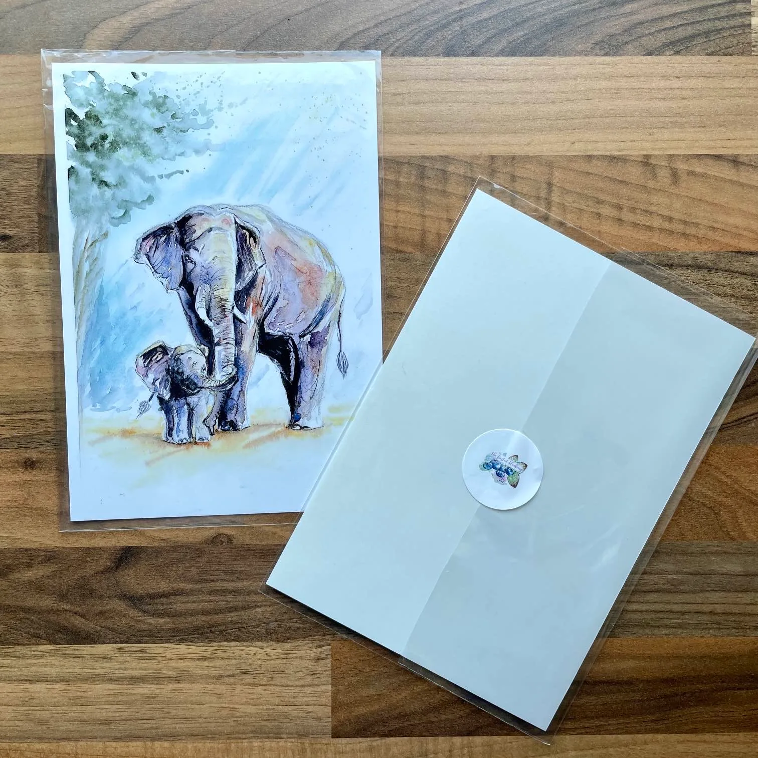 Watercolour of a mother and baby elephant holding trunks