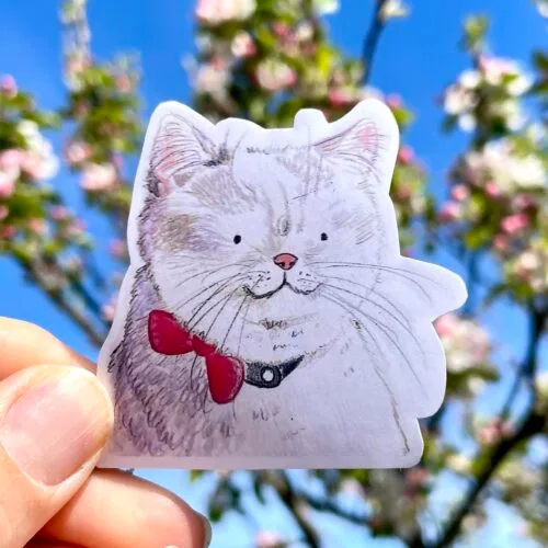 Vinyl die cut sticker of a white cat wearing a red bow